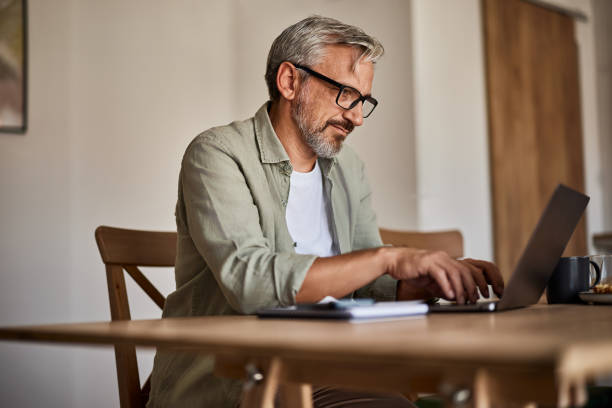 istock Mature man working on laptop at home, side view. 1623131816