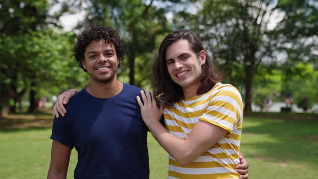 Portrait of young gay couple embracing at the park. LGBT and love concept. Same-sex family