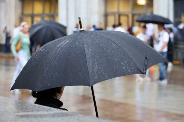 istock Man with black umbrella sitting on a street on people background 1623155482
