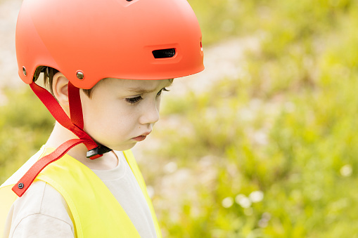Close up portrait of a 6 year old boy wearing a red bicycle helmet