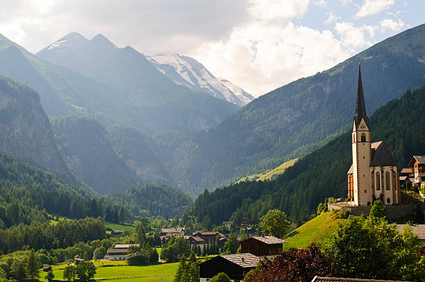 Church and landscape at Heiligenblut, Austria. Located at an elevation of 1,288 meters in the Austrian state of Carinthia, Heiligenblut is the southern gateway to the famous Großglockner Hochalpenstraße (Grossglockner High Alpine Road), which winds through the Hohe Tauern mountains. The Gothic church with the long spire was built in the late 1400s.
