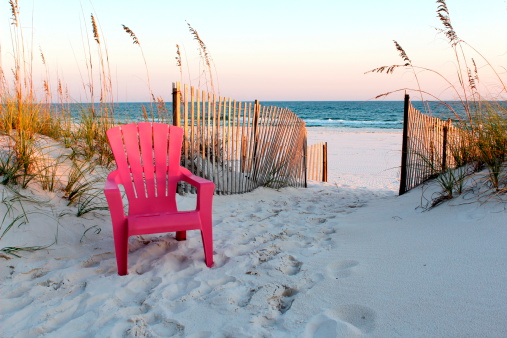 Taken at sunset in Gulf Shores, Alabama in 2011.  This is a single beach chair, positioned to the left of an open walkway to the beach.