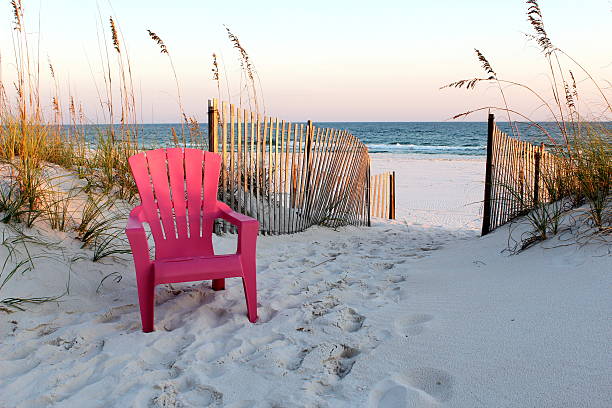 Beach chair leading to the Gulf of Mexico. Taken at sunset in Gulf Shores, Alabama in 2011.  This is a single beach chair, positioned to the left of an open walkway to the beach. gulf coast states stock pictures, royalty-free photos & images