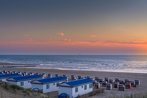 Katwijk aan Zee, The Netherlands - June 11, 2015: View from the dunes on the beach houses and cabins during sunset in Katwijk