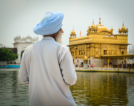 Amritsar, India - Jul 25, 2015. An old man praying at the Golden Temple in Amritsar, India. Golden temple is also known as Harmandir Sahib, a significant Sikh temple, which is located in Amritsar.
