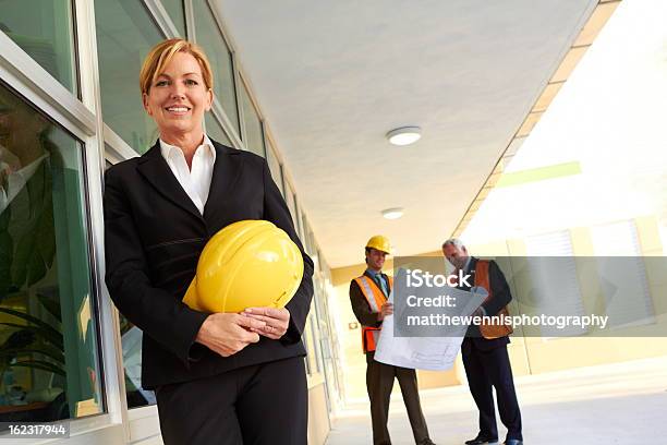Happy Zuversichtlich Businessfrau Mit Bau Arbeiter Im Hintergrund Stockfoto und mehr Bilder von 40-44 Jahre