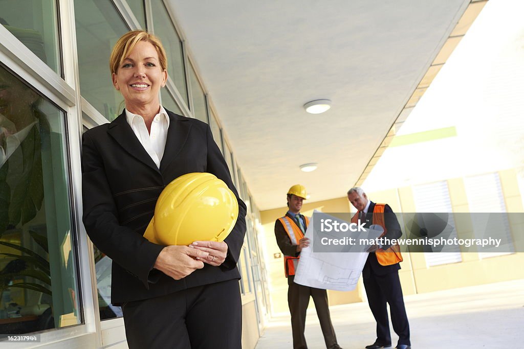 Felice fiducioso business donna con costruzione lavoratori in background - Foto stock royalty-free di 40-44 anni