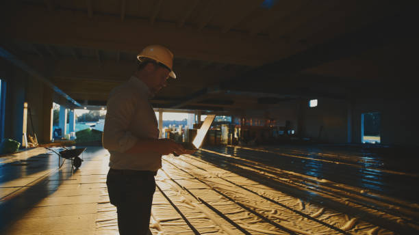 istock Mature male project manager with protective headwear using laptop at construction site 1623197906