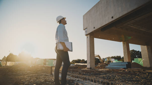 istock Mature male engineer with hardhat holding laptop while looking at building under construction 1623198026