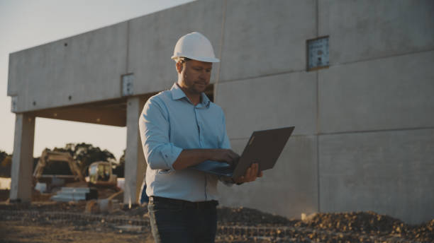 istock Male engineer with laptop near construction building during sunset 1623198033