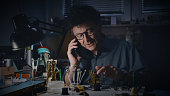 Male watch maker talking on mobile phone in the repair shop