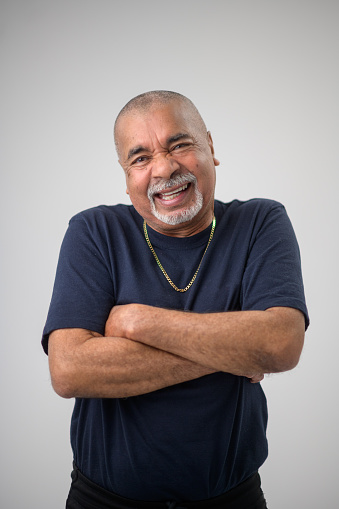 Senior Male Studio Portrait arms crossed laughing.  He has a goatee beard and his arms are crossed