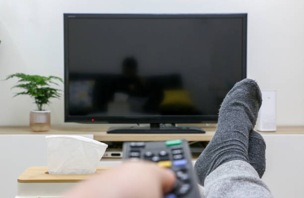 istock First-person view holding remote control about to turn on television screen, screen is black in the background. Feet up, nice and relaxed at home. 1623205834