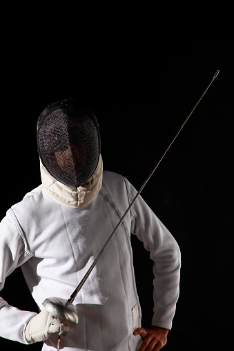 Fencer in a fencing pose. White on black background.