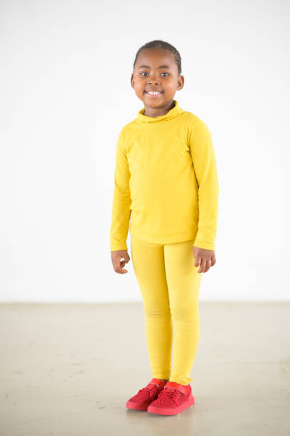Full length Cute Young African Girl in yellow with pink shoes studio portrait stock photo