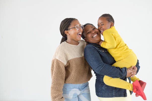 Happy African mother with two daughters studio portrait laughing out load together stock photo