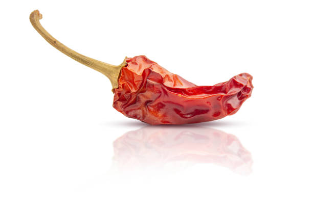 Dry red hot chili pepper reflects off the surface. Isolated on white background.