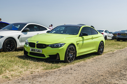 Tarporley, Cheshire, England, June 3rd 2023. Yellow BMW M4 Competition at a car meet, automotive culture editorial illustration.