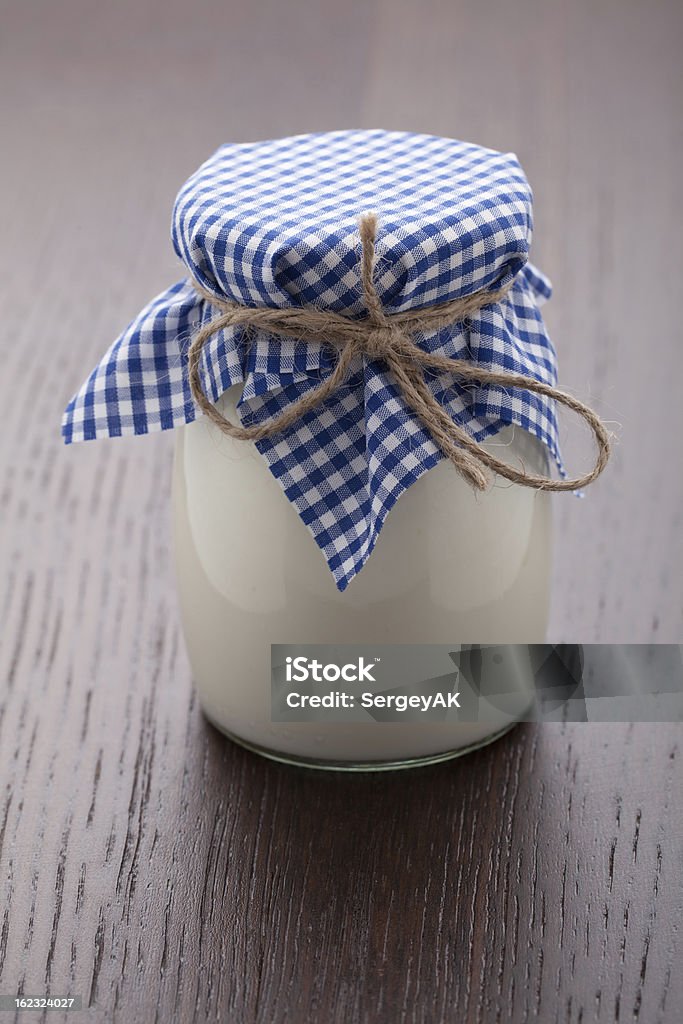 Homemade milk yogurt in glass pot on wooden table Homemade milk yogurt in glass pot served with linen napkin on wooden table Breakfast Stock Photo