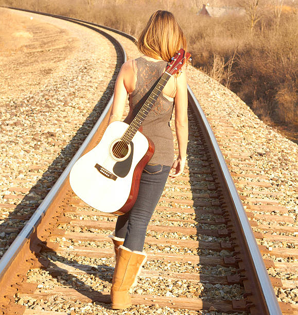 istock Young Lady Walking On Railroad Tracks With Guitar 162324277