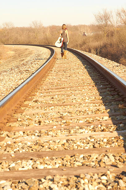 junge frau zu fuß auf bahngleise mit gitarre - leaving loneliness women railroad track stock-fotos und bilder