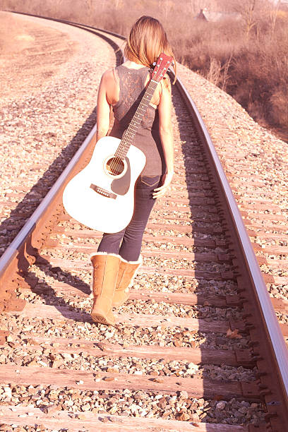 junge frau zu fuß auf bahngleise mit gitarre - leaving loneliness women railroad track stock-fotos und bilder