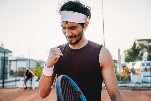 A tennis player is celebrating his victory. He has just scored the decisive point.