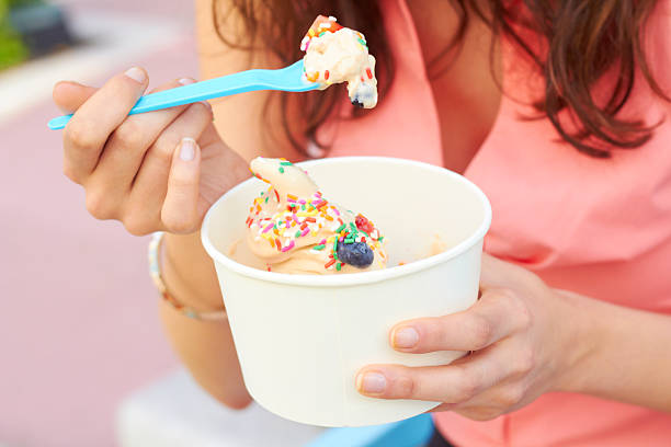 mujer comiendo frozen yogurt con bayas - yogur helado fotografías e imágenes de stock