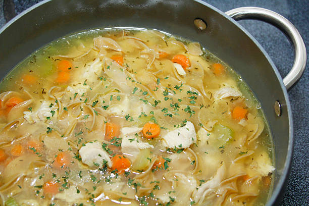Large pot of homestyle chicken noodle soup Homemade chicken noodle soup in pot with carrots, celery, topped with parsley bits. noodle soup photos stock pictures, royalty-free photos & images