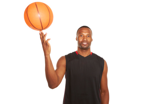 portrait of a happy young basketball player spinning ball on finger isolated on white.