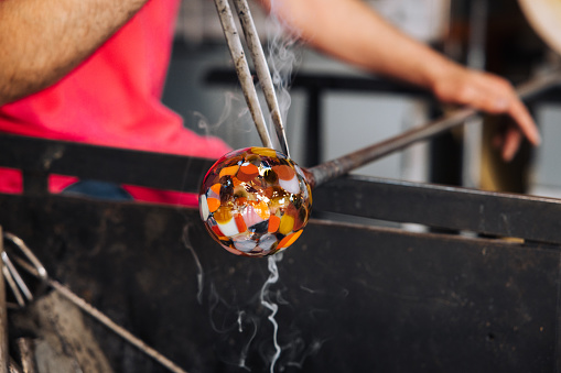 Glassblower crafting a Christmas bauble, from the heat of the oven to shaping it. Workshop based in France.