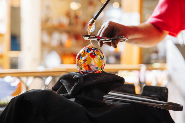 Glassblower crafting a Christmas Ornament Glassblower crafting a Christmas bauble, from the heat of the oven to shaping it. Workshop based in France. hand blown glass stock pictures, royalty-free photos & images