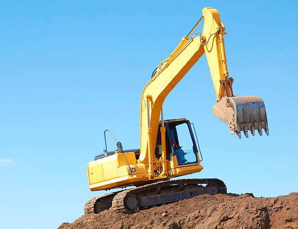 Excavation Machine On Heap Of Soil Yellow excavation machine on a heap of soil against clear sky. http://i1100.photobucket.com/albums/g409/matthewennisphotography/Constructionbanner1.jpg Earthmoving stock pictures, royalty-free photos & images