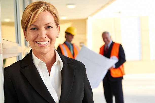 istock happy confident business woman with construction workers in the background 162333105