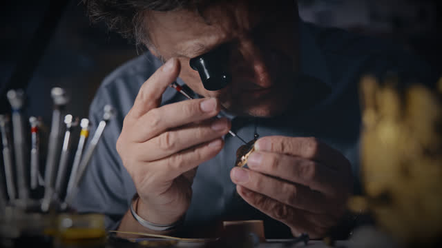 Focused male watchmaker with loupe fixing wristwatch