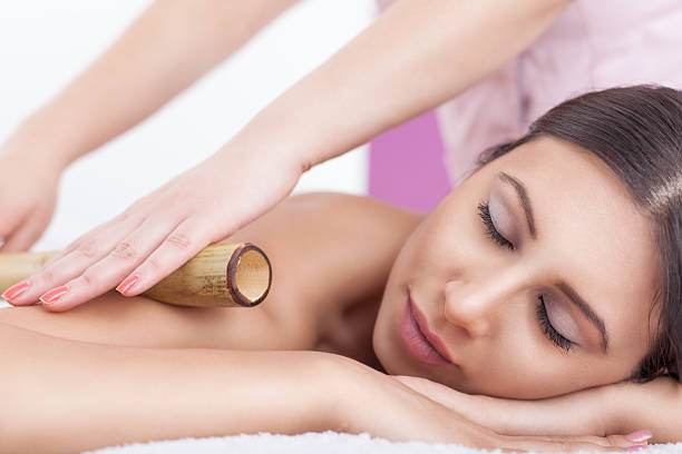 A young women getting her muscles rolled out Young Woman Enjoy Bamboo massage at spa centre. Selective focus,shallow DOF bamboo material stock pictures, royalty-free photos & images