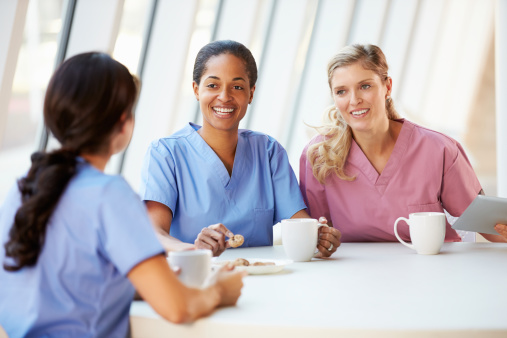 Group Of Nurses Chatting In Modern Hospital Canteen On Break Smiling