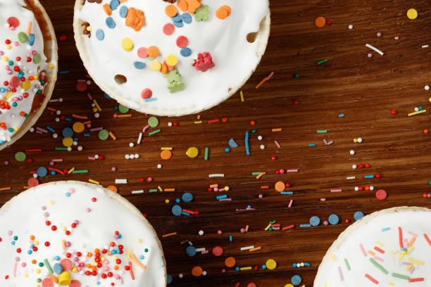 Four cupcakes or muffins decorated. Festive background. Confectionery confetti, balls lie on a on wooden background. Directly above