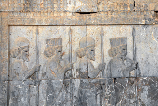 Ancient wall with bas-relief with four assyrian warriors with spears, Persepolis, Iran. UNESCO world heritage site