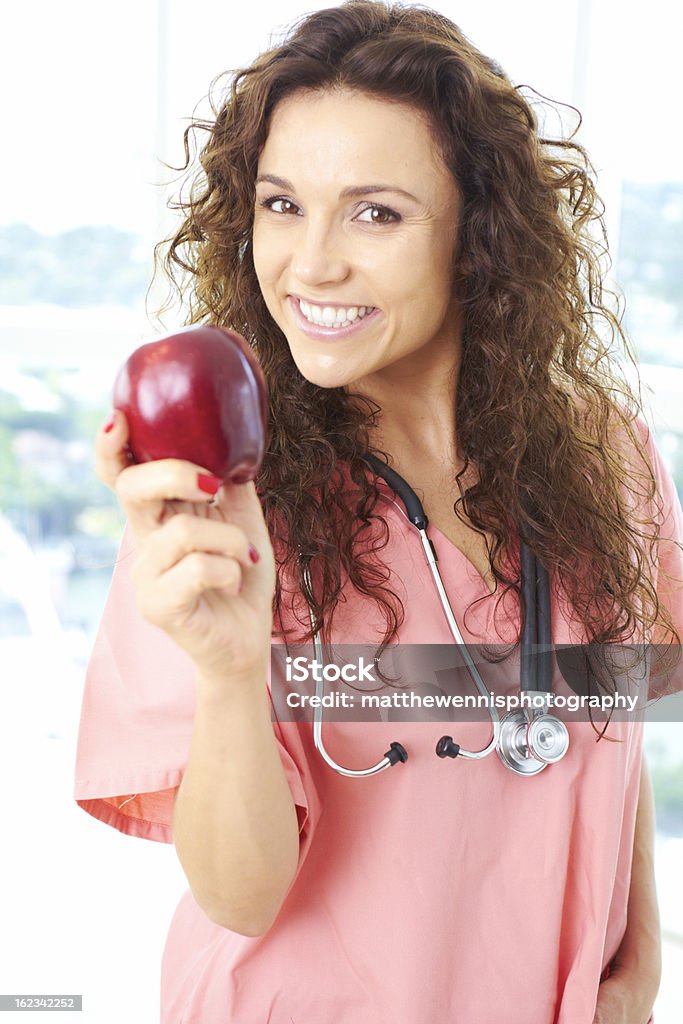 Glückliche junge Krankenschwester hält einen Apfel - Lizenzfrei Apfel Stock-Foto