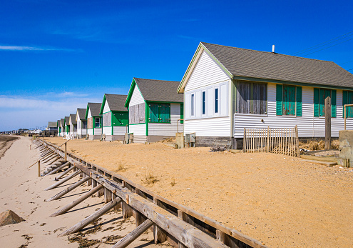A row of identical beachside cottages on the road leading to Provincetown, Massachusetts on a mild mid March afternoon wait for summer visitors.