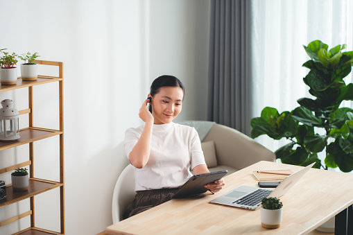 Asian woman enjoy with working online using tablet sitting at home office. Happy woman working from home.