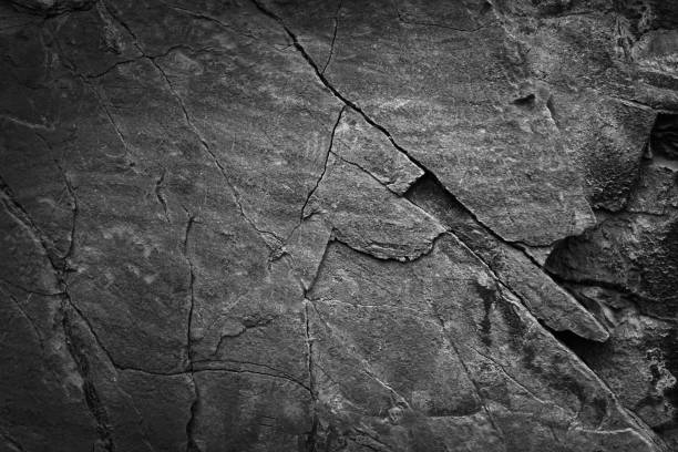 Black white dark gray grunge background. Stone rock texture. Rough mountain surface. Close-up. It looks like a concrete wall. Cracked broken. Black white dark gray grunge background. Stone rock texture. Rough mountain surface. Close-up. It looks like a concrete wall of a house. Cracked broken scratched old damaged dirty. For design. natural granite rough stone stock pictures, royalty-free photos & images