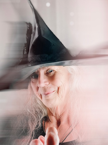 close-up of a white-haired witch in a black hat and costume on a white background