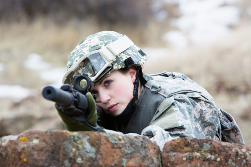 Young attractive female soldier with a long barrel rifle