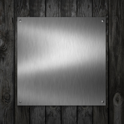 Brushed metal plates with rivet on wooden wall.