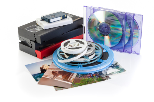 Video cassettes, photographs and film reels on white background with DVD, Concept for DVD transfer. +++Photographs shown were taken by photographer.++