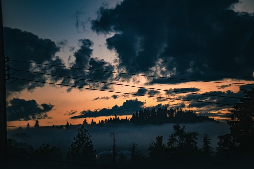 A dramatic dark sky with power lines running through the landscape