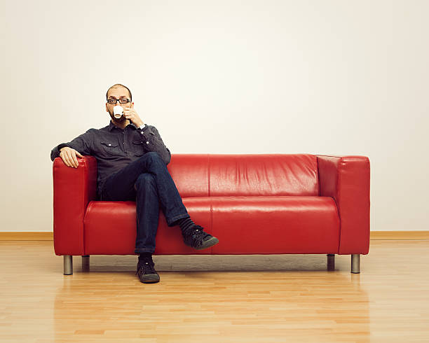 Coffee break Relaxed man having a coffee on a sofa. cross legged stock pictures, royalty-free photos & images