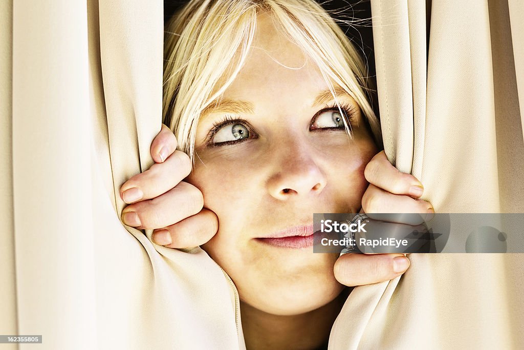 Loura engraçada peeping lado através de cortinas, a sorrir shyly - Royalty-free 20-29 Anos Foto de stock